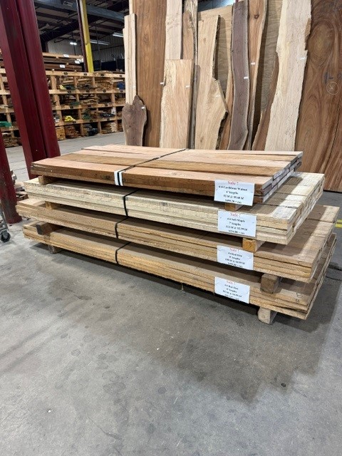 Four hardwood lumber bundles stacked on a pallet in the Frederick Lumber warehouse, each marked with a sale tag